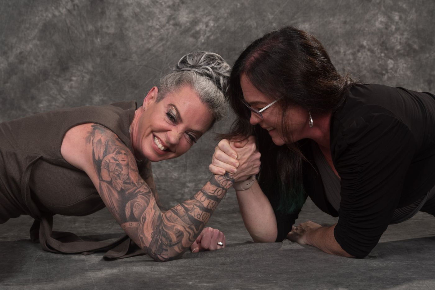 Carrie and Tracie arm wrestling on the floor