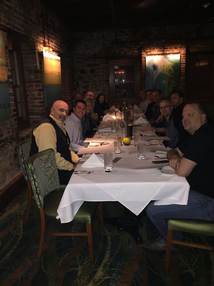 A long candlelit dinner table full of friends