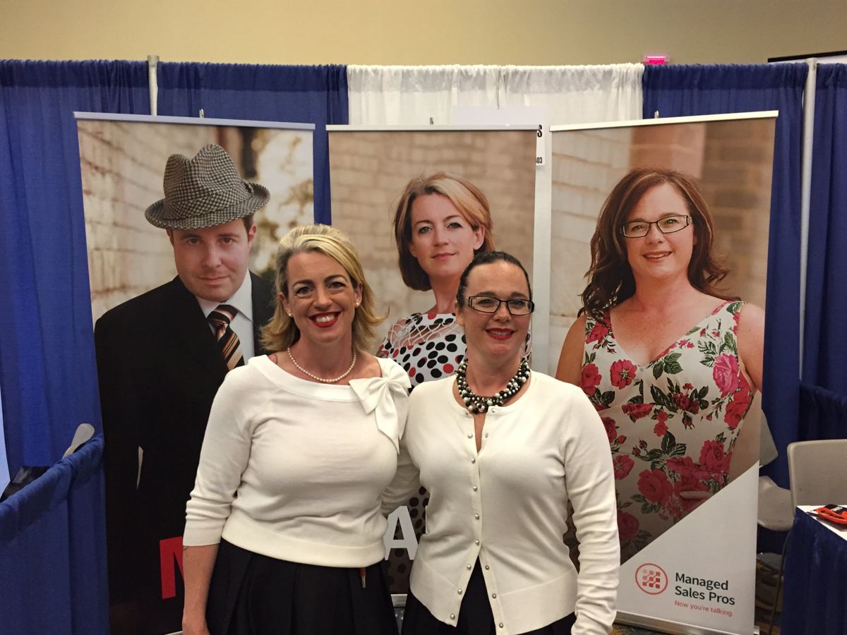 Carrie and Tracie in front of their booth banners